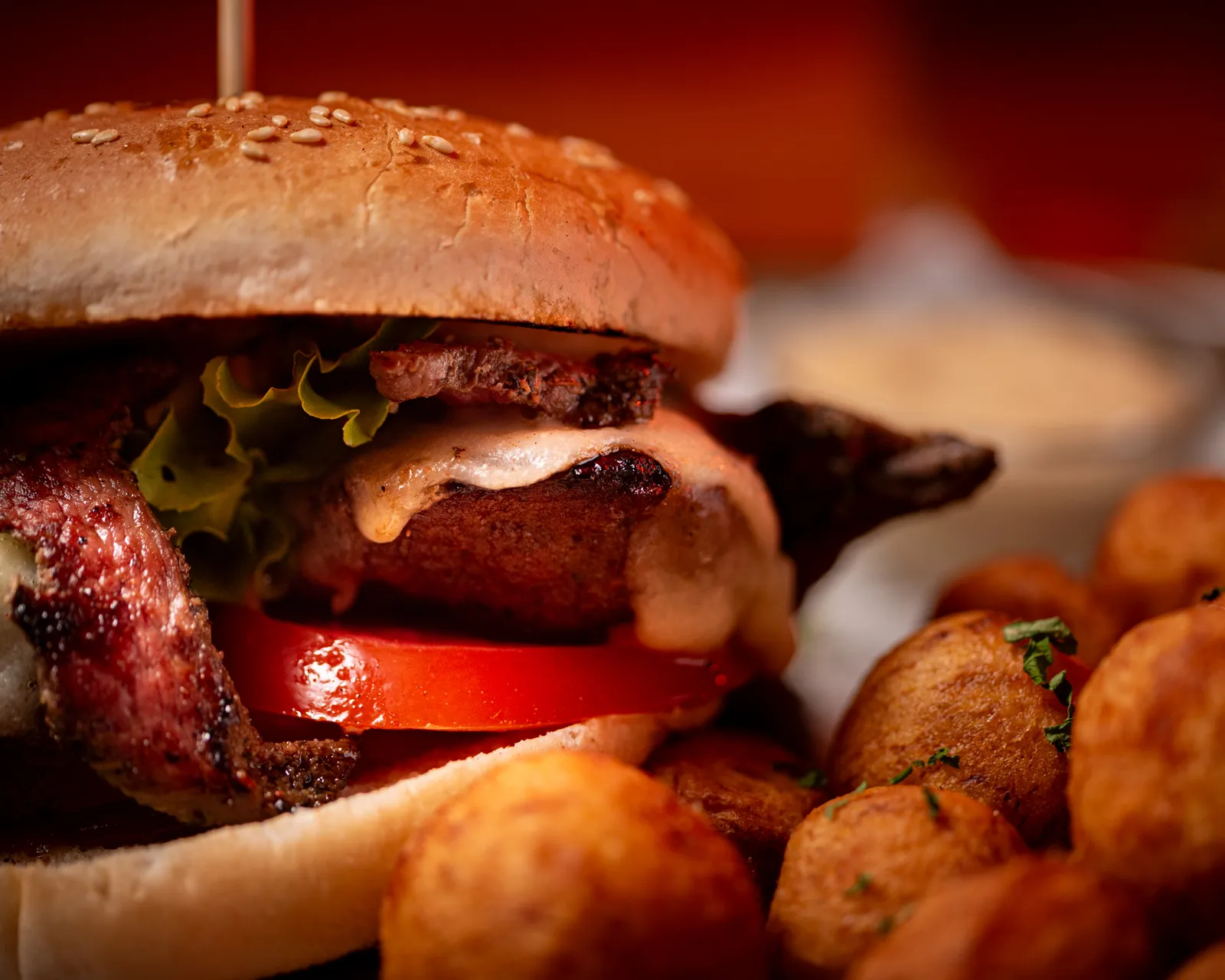 Prim-plan cu un burger suculent, cu bacon, cașcaval și roșie