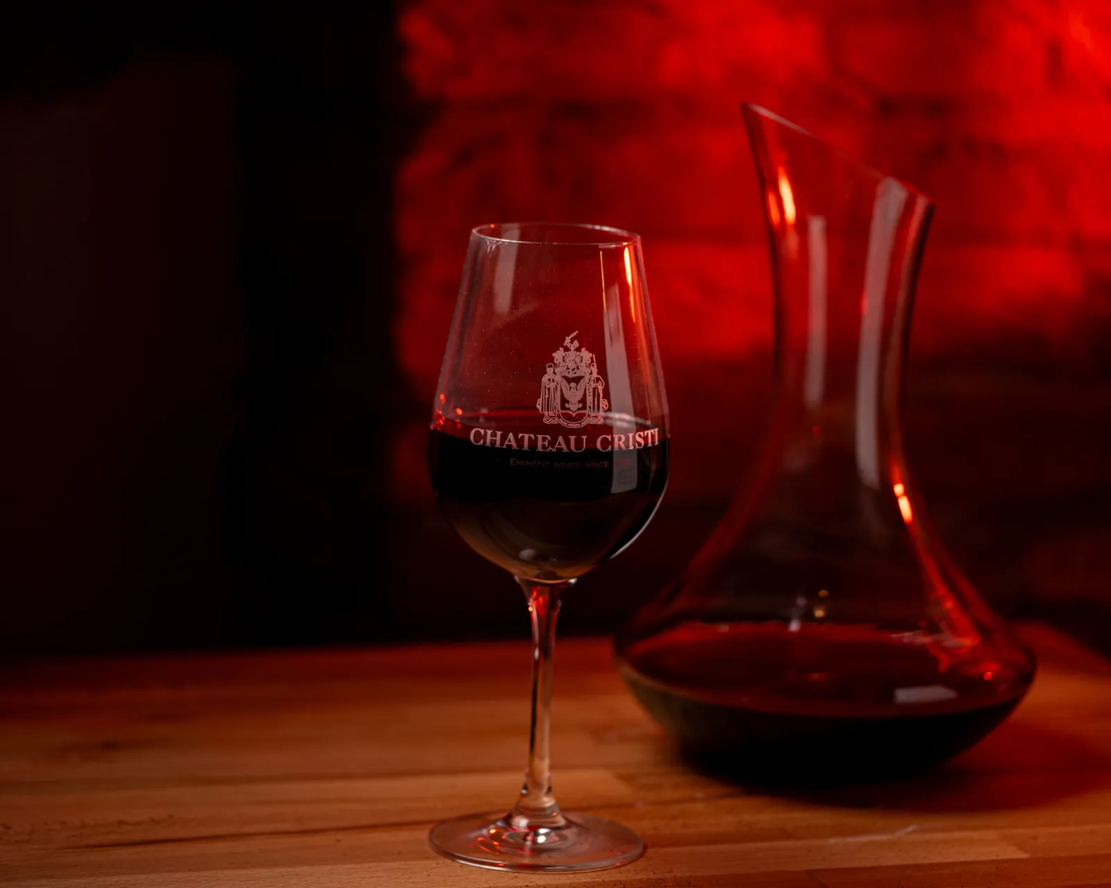 Pahar de vin roșu Chateau Cristi și decantor, în lumină caldă